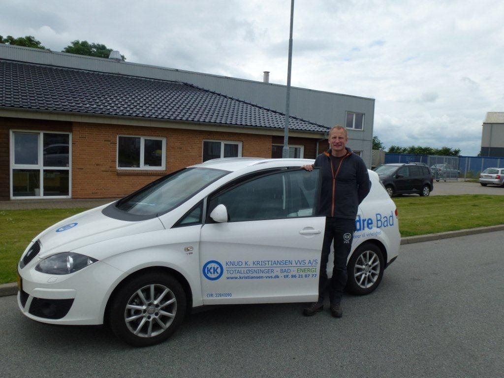Medarbejder hos Knud K. Kristiansen VVS A/S står ved siden af en firmabil med logo i Hinnerup, tæt på Aarhus og Risskov